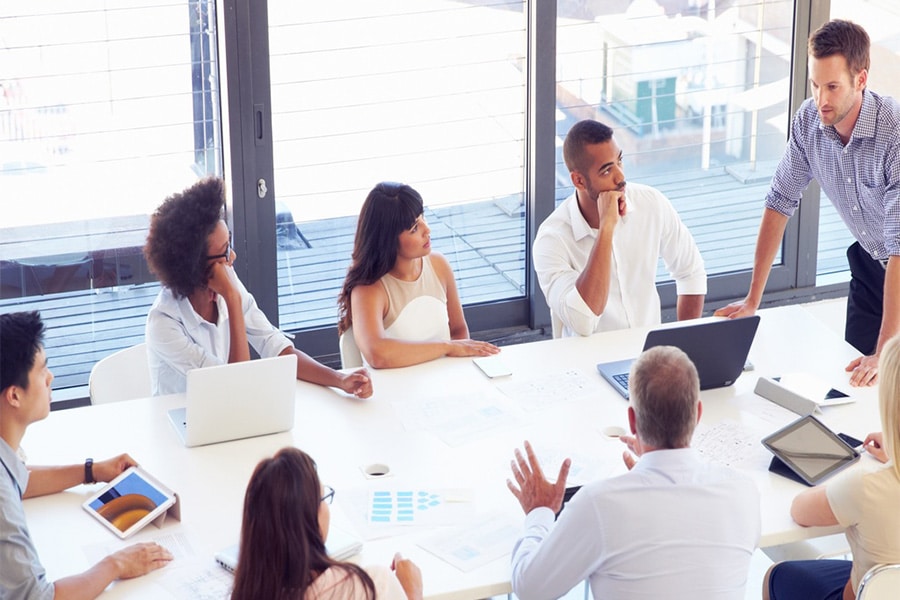 Diverse group of professionals engaged in a presentation meeting, discussing ideas and strategies to enhance presentation skills for improved employability and leadership.