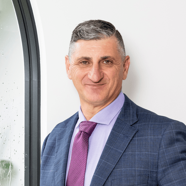 Mario Sultana, Principal at Brainpower Training, confidently smiling in a professional suit, emphasizing expertise in selling skills and workplace training.